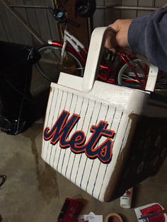 a new york mets ice chest with the word mets on it and a bicycle in the background