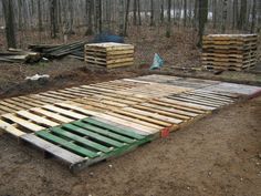 several wooden pallets in the middle of a wooded area with trees and logs around them