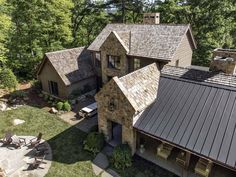 an aerial view of a stone house with metal roofing and outdoor seating area in the foreground