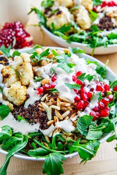 two bowls filled with salad and dressing on top of a wooden table next to each other