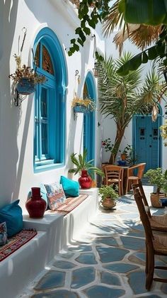 an outdoor seating area with potted plants and blue doors on the side of a building