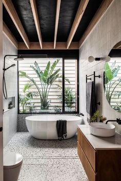 a bathroom with two sinks and a bathtub in the middle, surrounded by plants