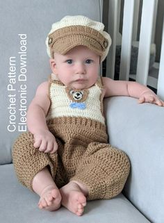 a baby wearing a crochet hat and overalls sitting on a gray couch