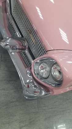 the front end of an old pink car with chrome grills and hood vents on it