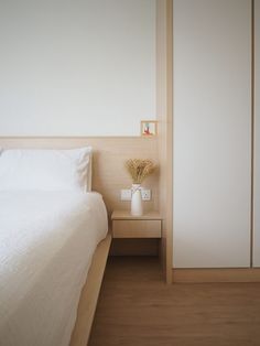 a white bed sitting next to a wooden nightstand