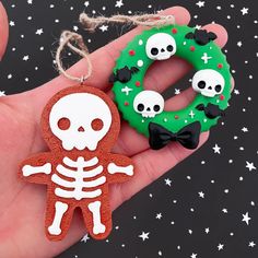 a hand holding a christmas ornament with two skulls and a wreath on it