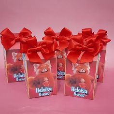 three small bags with red bows on them are sitting in front of a pink background