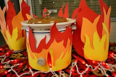 three fire buckets sitting on top of a table covered in red and yellow paper