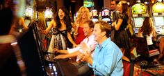 two men playing video games in front of a group of people at a casino machine