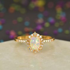 an opal and diamond ring sitting on top of a table