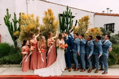 a group of people standing next to each other in front of a building with cacti