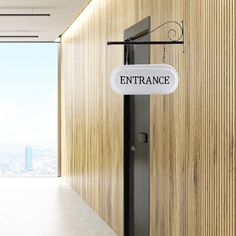 an entrance sign hanging from the side of a wooden wall next to a doorway with a city view