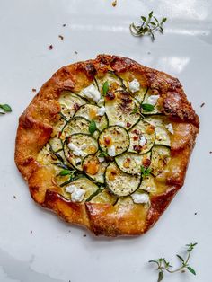 a pizza topped with cucumbers and cheese on top of a white plate