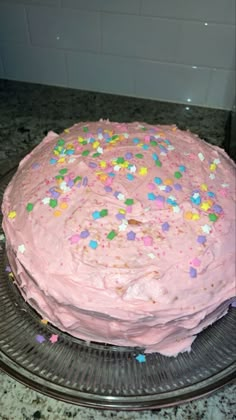 a cake with pink frosting and sprinkles on it sitting on a plate