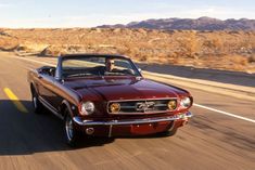 a red mustang convertible driving down the road