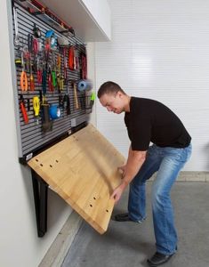 a man is working on a wall mounted tool rack