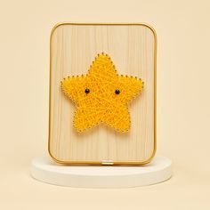 a yellow star brooch sitting on top of a white stand next to a beige wall