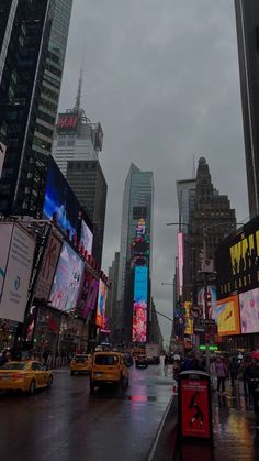 a city street filled with lots of traffic and tall buildings covered in billboards under cloudy skies