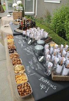 a long table topped with lots of food and drinks on top of a black cloth covered table