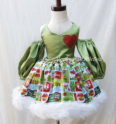 a green dress with red heart on the chest and white fur trimming around it