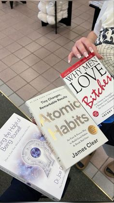 a person holding two books in one hand and another on the other with writing on them