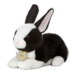 black and white rabbit stuffed animal with name tag on it's collar, laying down