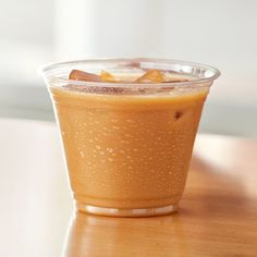 a drink in a plastic cup sitting on top of a wooden table