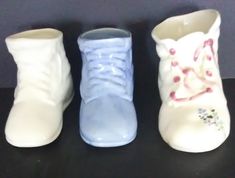 three white and blue vases sitting next to each other on a black counter top