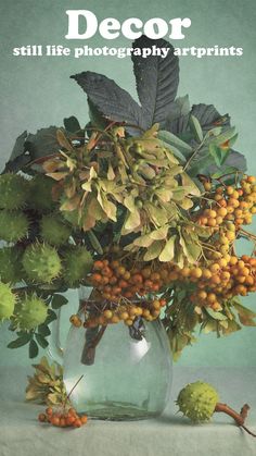 a vase filled with lots of flowers on top of a white tablecloth next to green leaves and berries