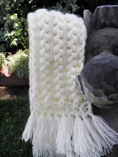 a white crocheted blanket sitting on top of a wooden statue