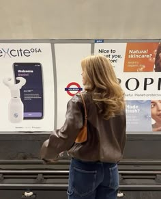 a woman standing in front of a sign with advertisement on the wall next to her