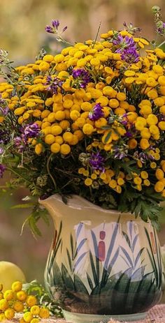 a vase filled with lots of yellow and purple flowers