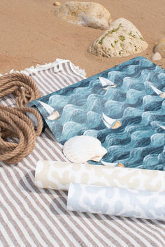 there is a towel on the beach next to some ropes and seashells in the sand