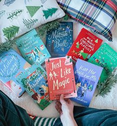 a person is sitting on the floor with some books in front of them and christmas pillows