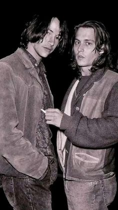 two young men standing next to each other in front of a black and white photo