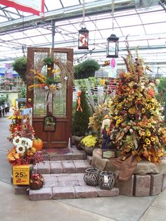 a display in a greenhouse filled with lots of plants and decorations on the front steps