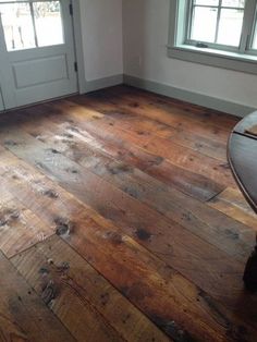 an empty room with wooden floors and white walls, two windows on the far side