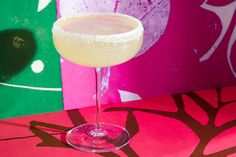 a glass filled with a drink sitting on top of a red table cloth next to a colorful wall