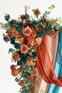 an arrangement of flowers is hanging from the ceiling with blue and orange ribbons on it