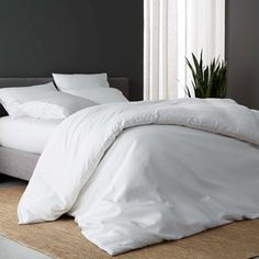 a bed with white sheets and pillows in a room