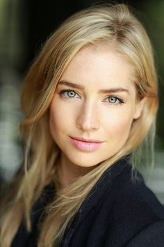 a woman with blonde hair and blue eyes looks at the camera while wearing a black jacket