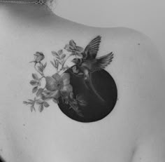 a woman's back with flowers and a bird tattoo on her left shoulder, which is black and white