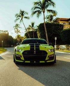 a yellow and black car parked on the side of a road next to palm trees