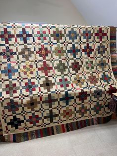 a couch covered in a multicolored quilt next to a table with a chair