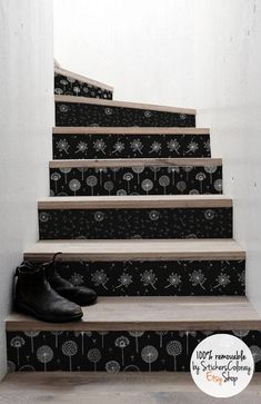 a pair of black shoes sitting on top of a set of stairs with dandelions