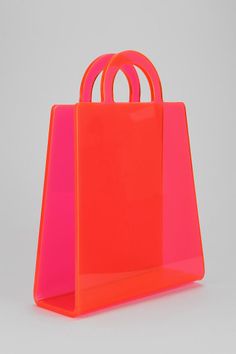 an orange and pink shopping bag sitting on top of a white surface with two handles