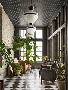 a living room with black and white checkered flooring, large potted plants