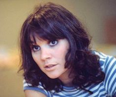 a close up of a person wearing a striped shirt and looking at the camera with a serious look on her face