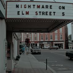 people are walking under the marquee for nightmare on elm street 5, which is located in downtown