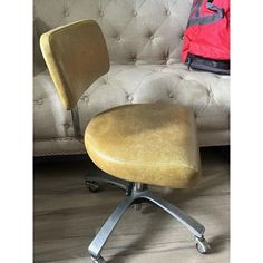 a yellow office chair sitting on top of a wooden floor next to a white couch